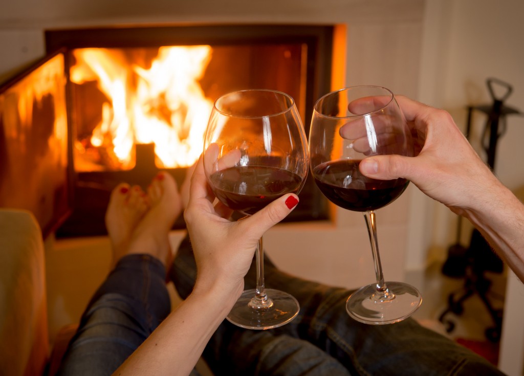 couple drinking wine in front of a fire