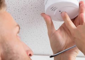 man checks carbon monoxide detector